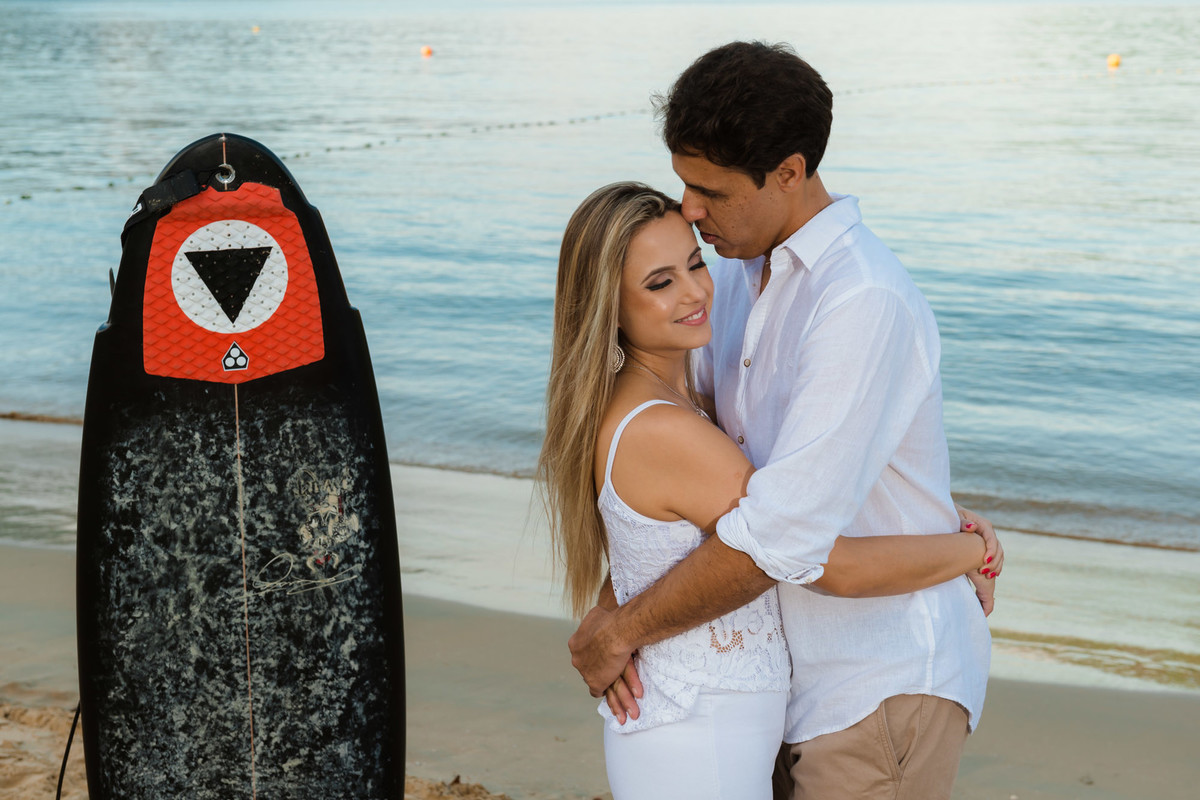 casal juntos com prancha de surf na praia
