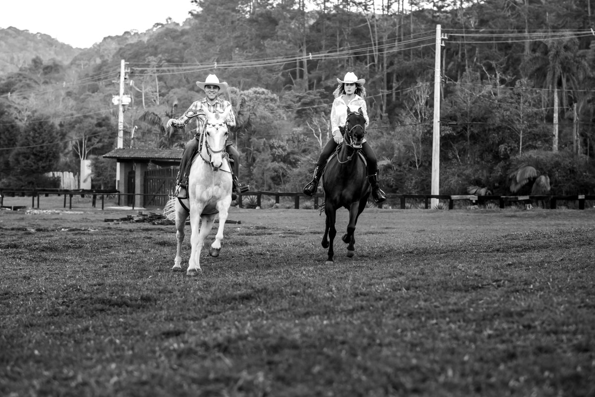 casal cavalgando na beira do lago com a luz do por do sol em sitio na cidade de Juquitiba