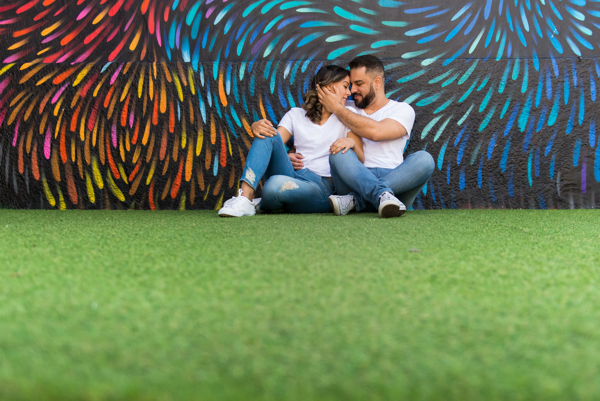 ensaio de casal sentados em grama sintetica no Beco do Batman na Vila Madalena