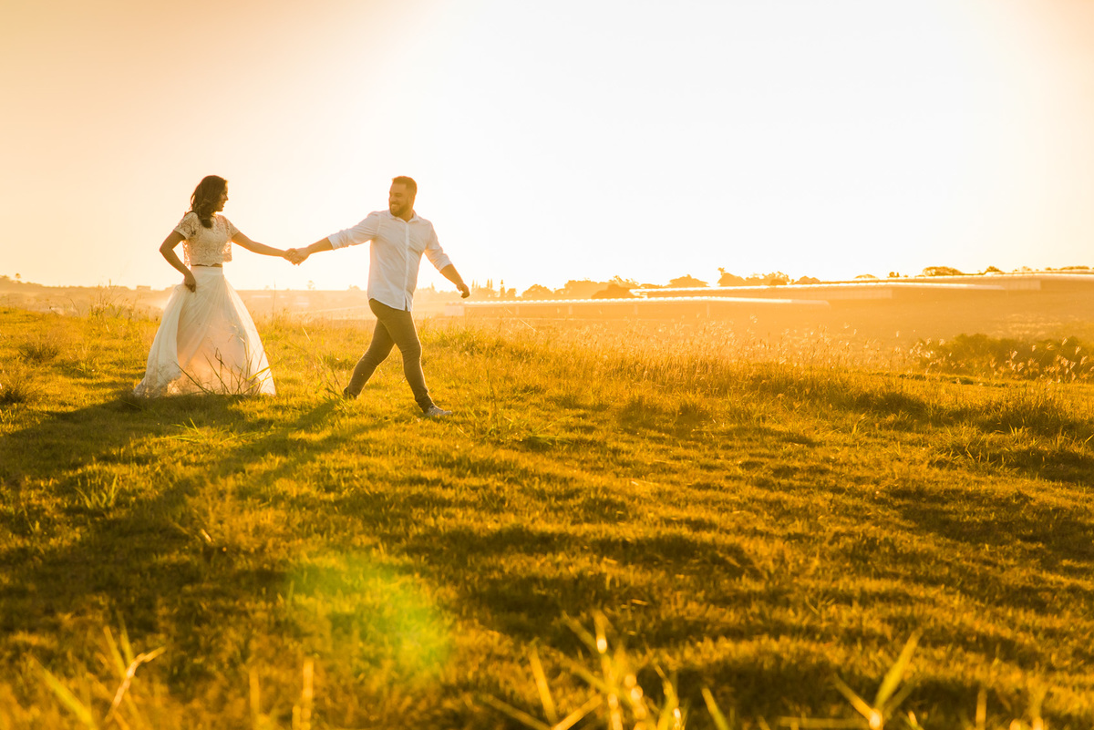ensaio de casal, pre-wedding noiva caminhando em campo de feno no por do sol em Holambra cidade das flores