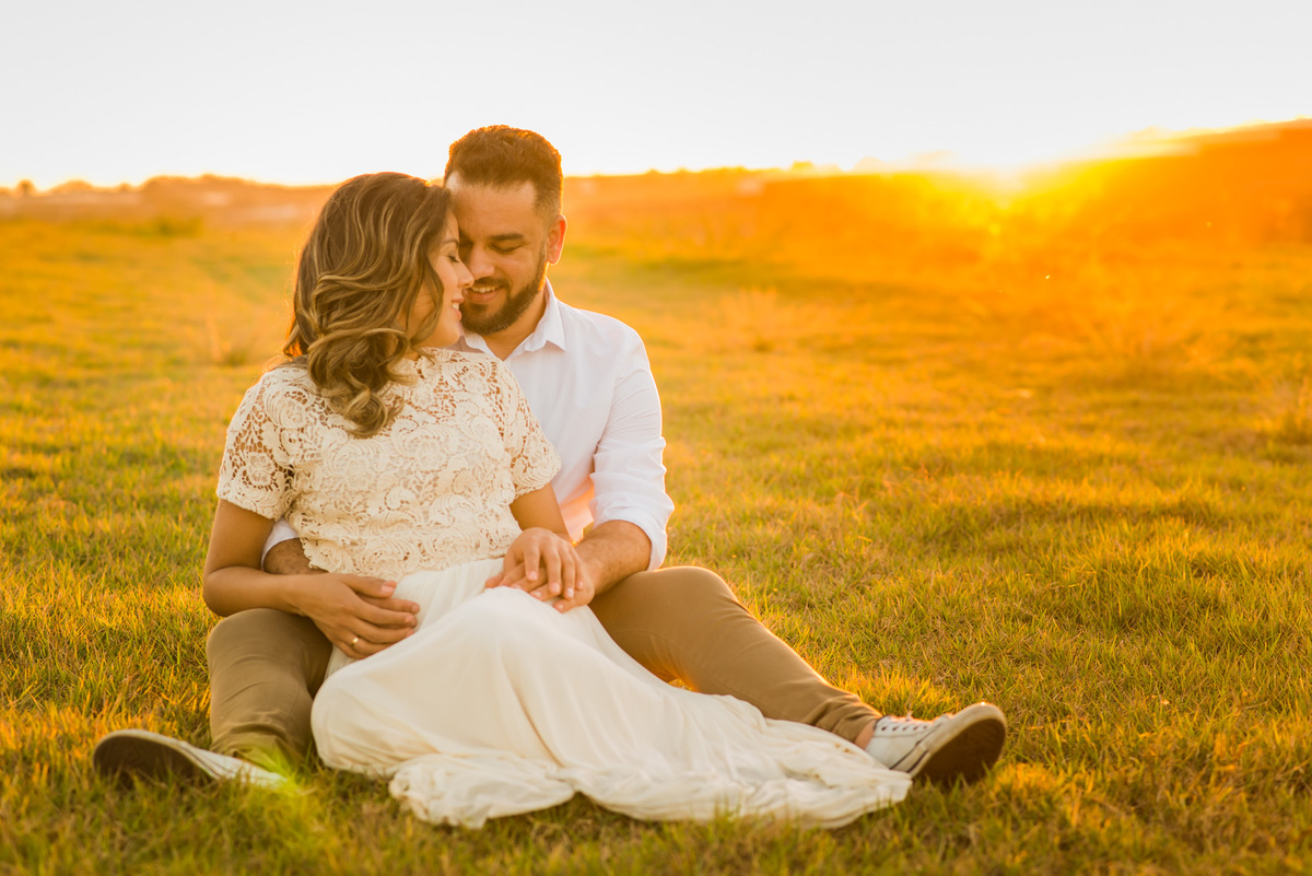 ensaio de casal, pre-wedding casal sentado se beijando em campo de feno no por do sol em Holambra cidade das flores