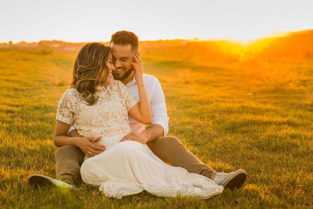 ensaio de casal, pre-wedding casal sentado se beijando em campo de feno no por do sol em Holambra cidade das flores