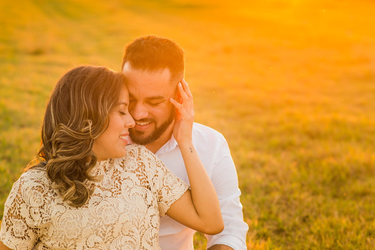 ensaio de casal, pre-wedding casal sentado se beijando em campo de feno no por do sol em Holambra cidade das flores