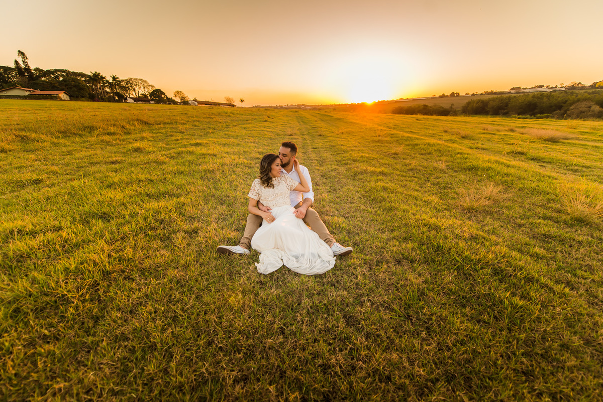 ensaio de casal, pre-wedding casal sentado se beijando em campo de feno no por do sol em Holambra cidade das flores