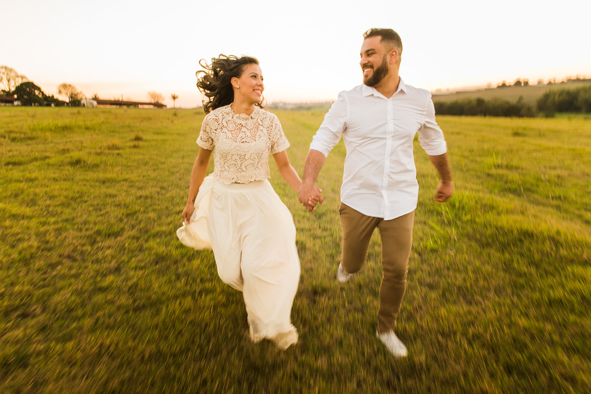 ensaio de casal, pre-wedding casal correndo em campo de feno no por do sol em Holambra cidade das flores