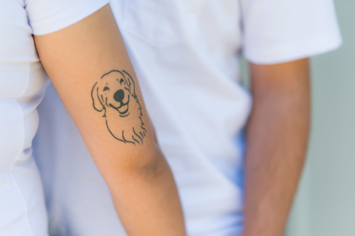 casal com a tatuagem do cachorro no braço na cidade de Paranapiacaba com arquitetura local ao fundo