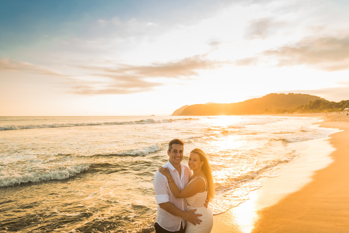 casal abraçados na praia com o por do sol ao fundo no litoral norte
