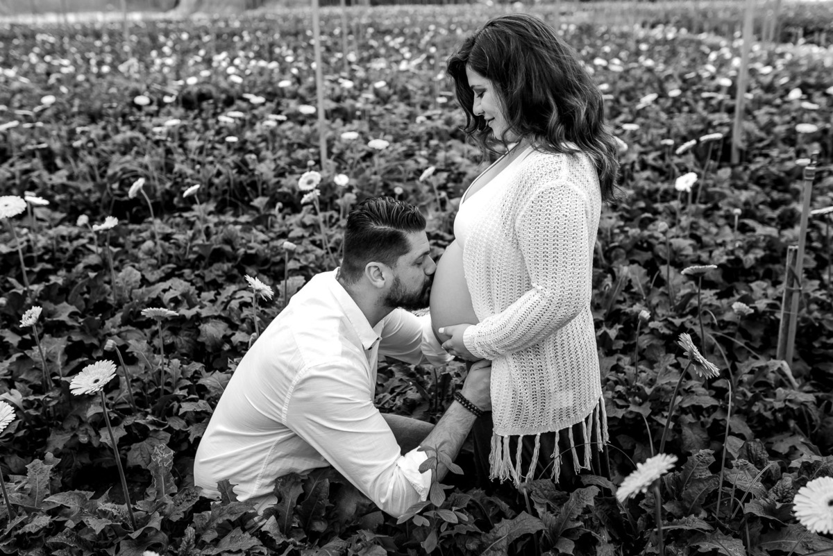 casal gestante se olham em estufa 
e campo de flores em Holambra - cidade das flores