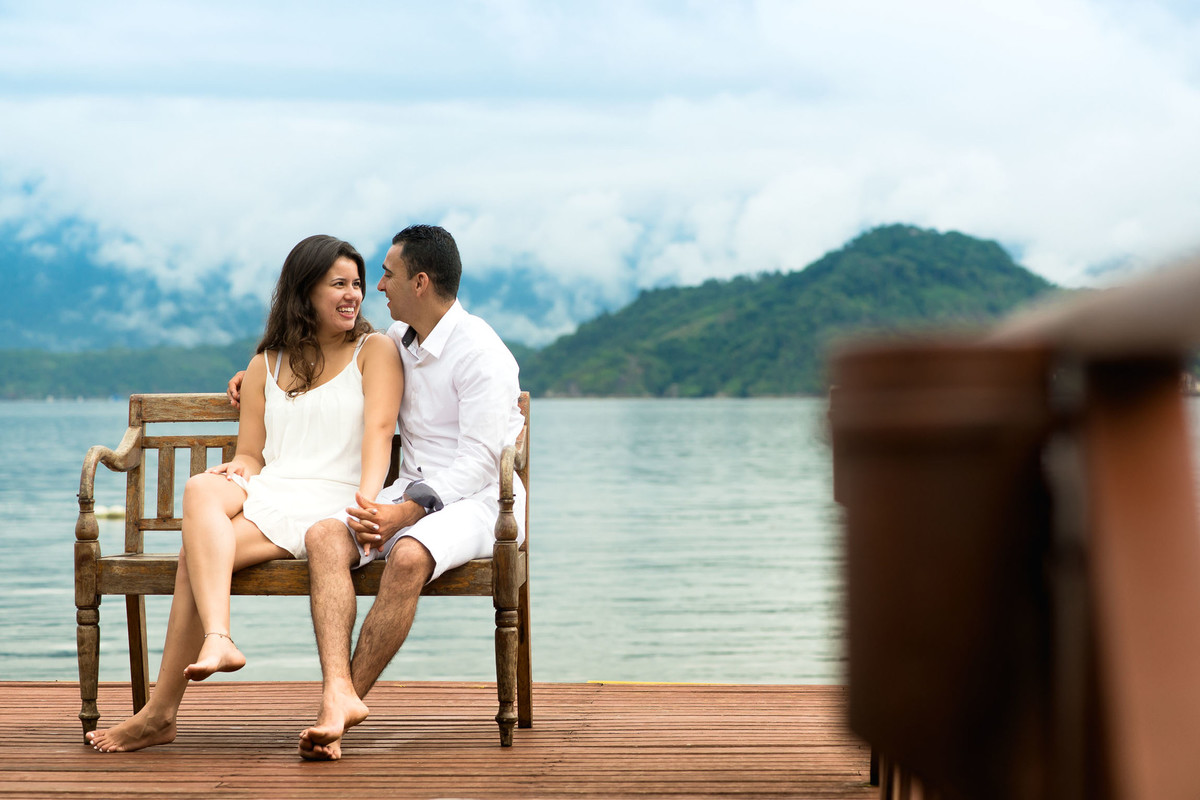 casal sentado em banco na praia de angra dos reis