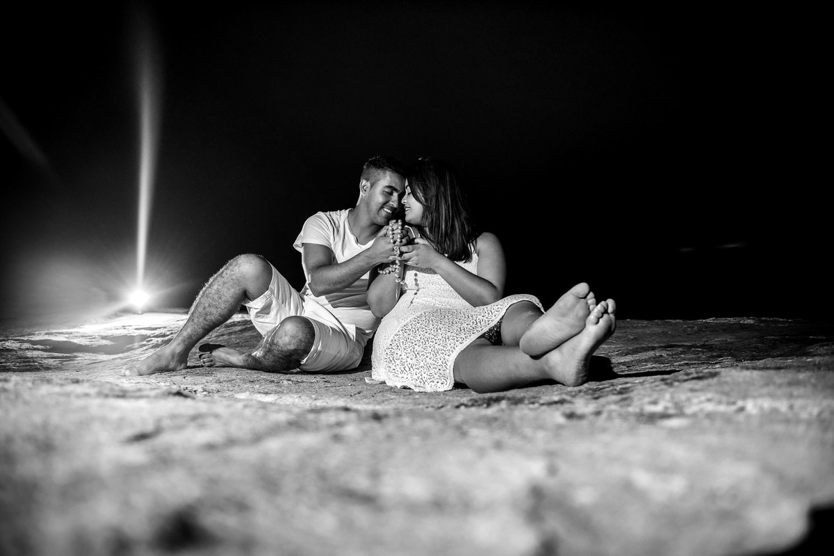 casal abraçados e rezando com terço na mão na praia do Iporanga no Guaruja em São Paulo