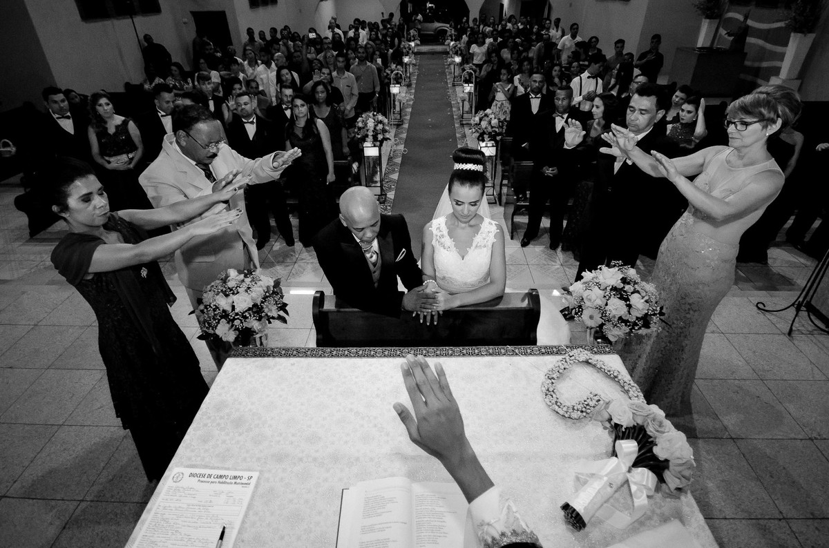 noivos de joelho sendo abençoados pelo padre e o pais na igreja Paroquia Santa Luzia em São Paulo