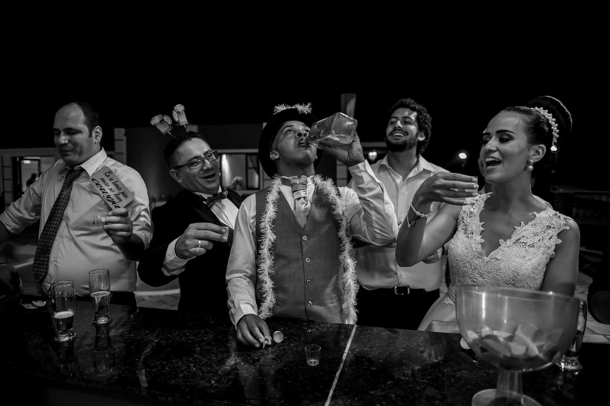 noivo bebendo tequila na garrafa e amigos rindo ao redor no buffet Reis Recepções