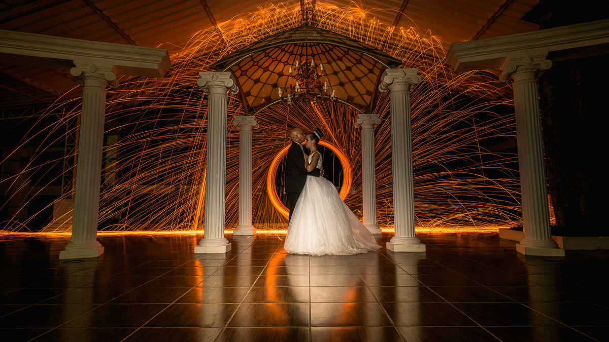 Noivos abraçados com roda de fogo ao fundo no buffet Reis Recepções