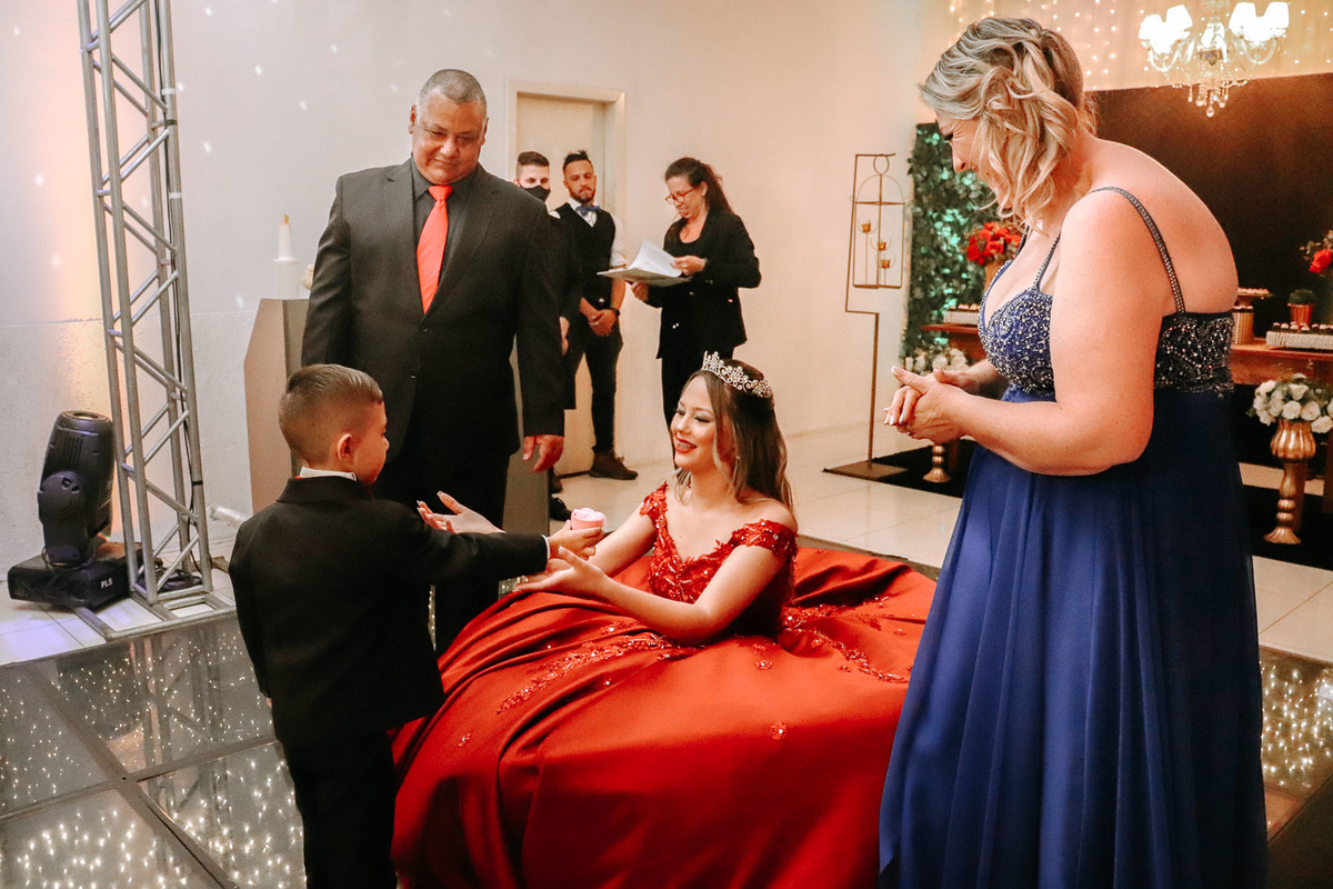 Luiza pronta para sua festa de 15 anos usando um vestido vermelho com pedrarias