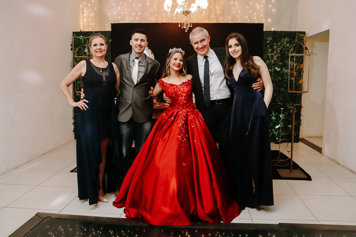 Luiza pronta para sua festa de 15 anos usando um vestido vermelho com pedrarias