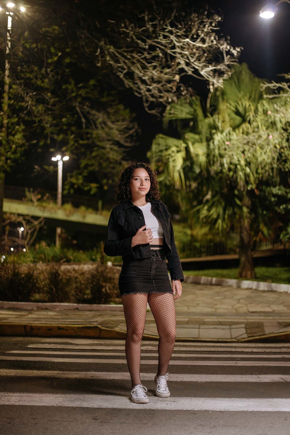 Ensaio de 15 anos em Canoas com estilo urbano noturno, debutante em frente a avião com iluminação dramática