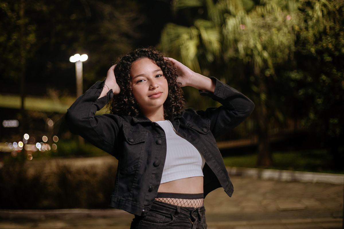 Ensaio de 15 anos em Canoas com estilo urbano noturno, debutante em frente a avião com iluminação dramática