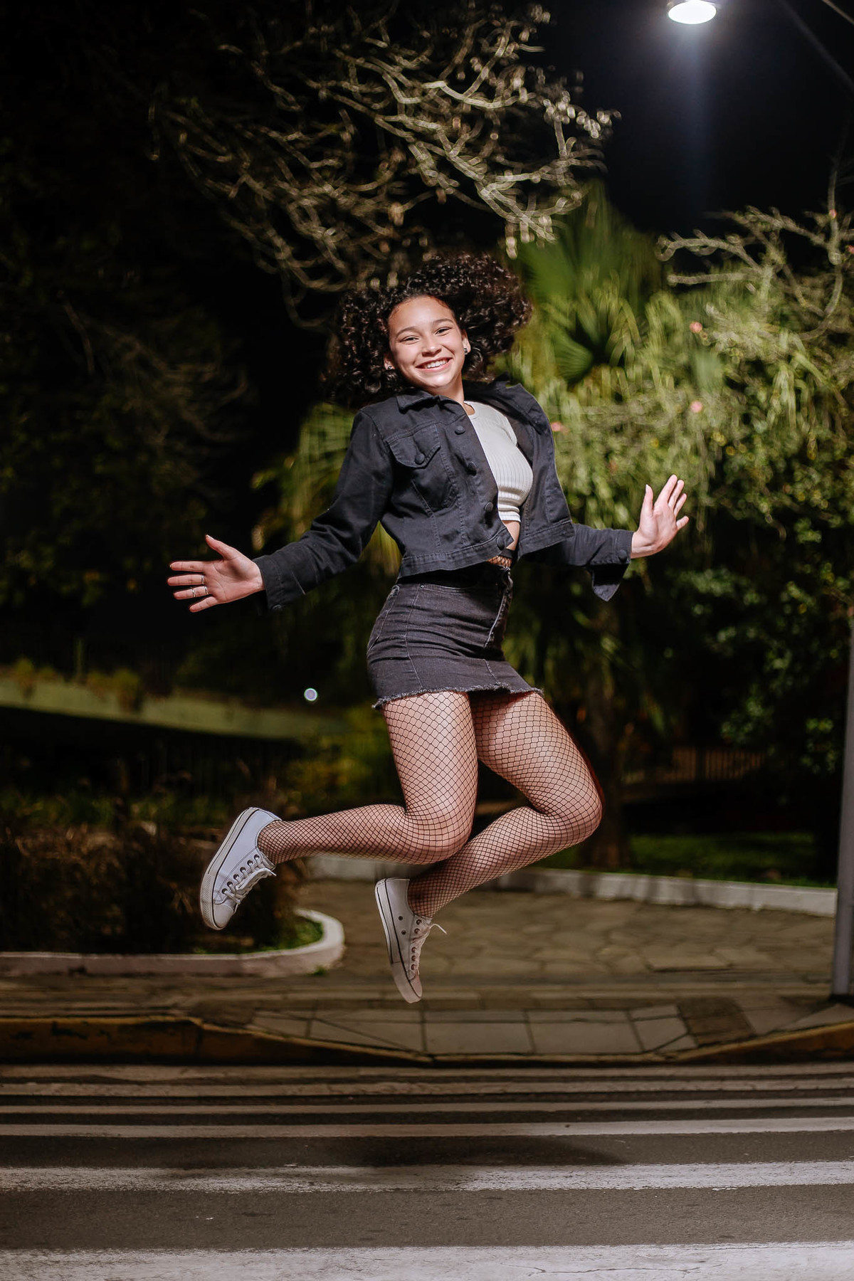 Ensaio de 15 anos em Canoas com estilo urbano noturno, debutante em frente a avião com iluminação dramática