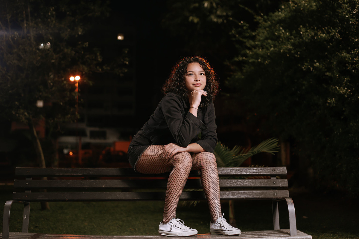 Ensaio de 15 anos em Canoas com estilo urbano noturno, debutante em frente a avião com iluminação dramática