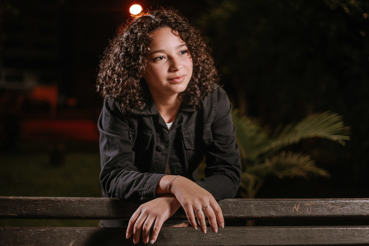 Ensaio de 15 anos em Canoas com estilo urbano noturno, debutante em frente a avião com iluminação dramática