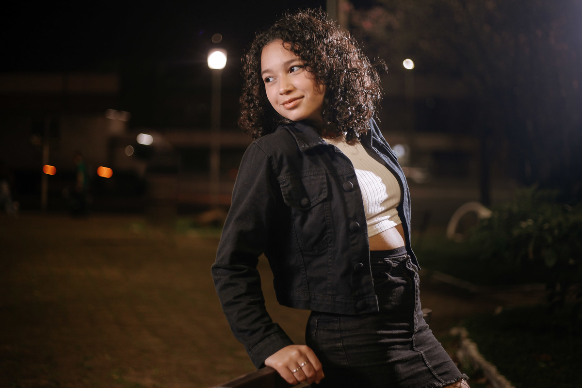 Ensaio de 15 anos em Canoas com estilo urbano noturno, debutante em frente a avião com iluminação dramática