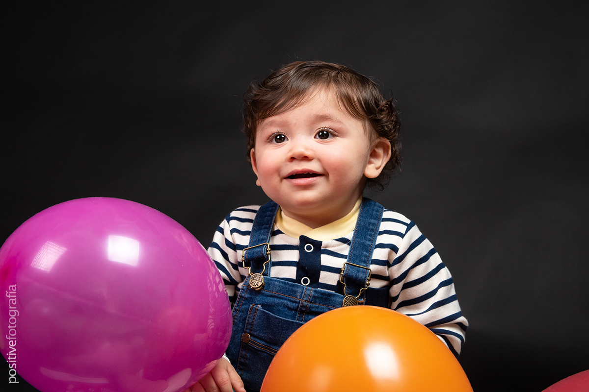 Niño sonriente detrás de globos de colores