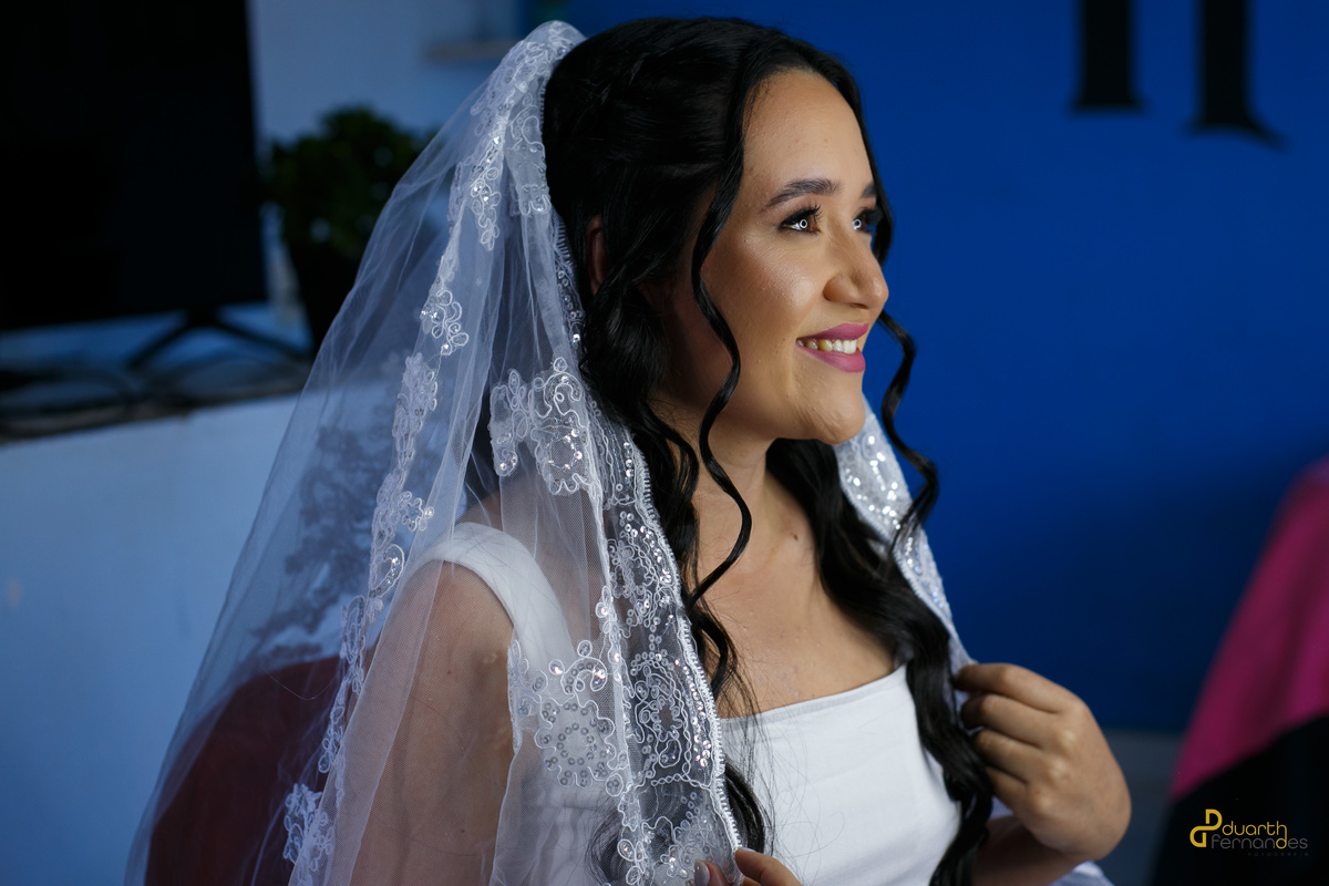 Noiva Mariana com véu de lado sorrindo, foto preto e branco, capturando a alegria antes do casamento.