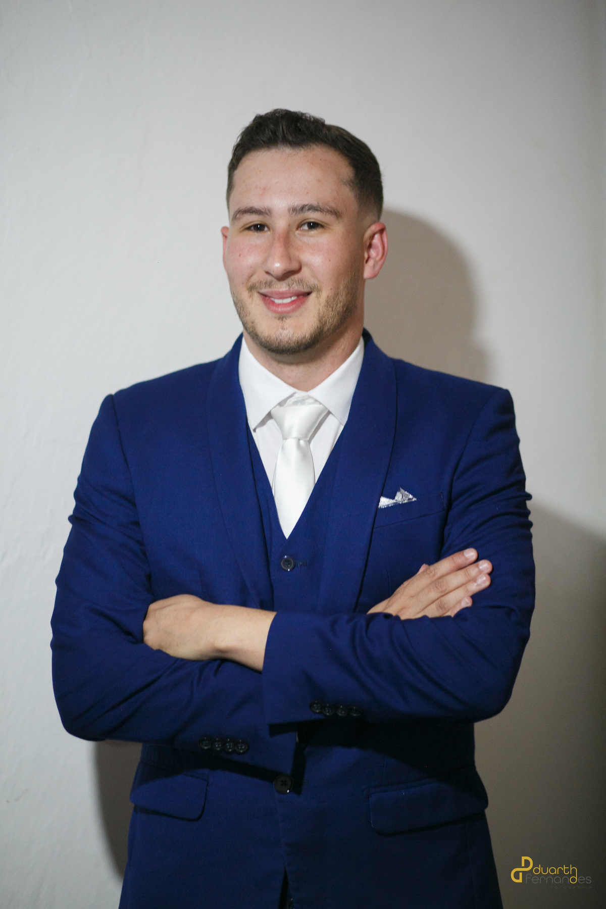Retrato do noivo Lucas, terno azul vibrante, colete e gravata branca, posando confiant