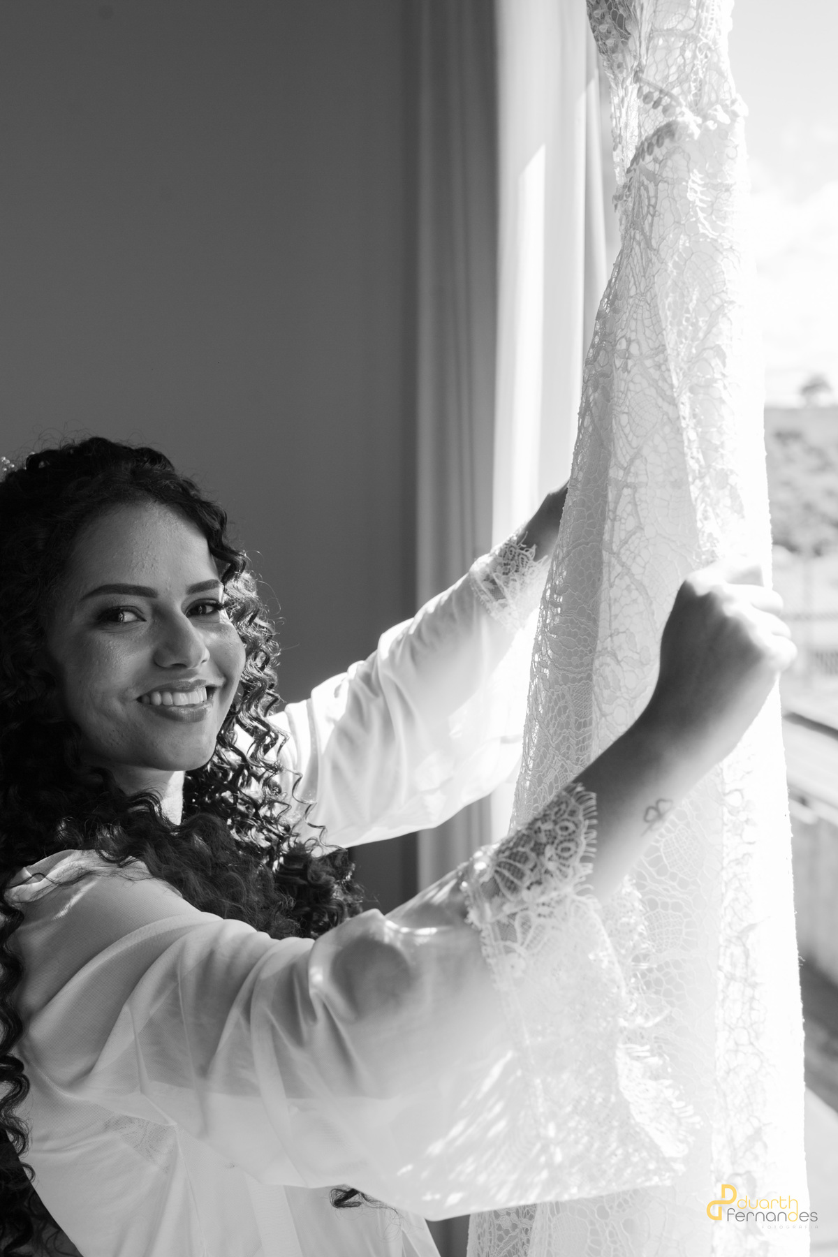 Noiva Jacyara ajustando seu vestido antes da cerimônia de casamento, enquanto seu amigo a ajuda a se preparar com carinho. Fotografia de casamento em ambiente natural e elegante.