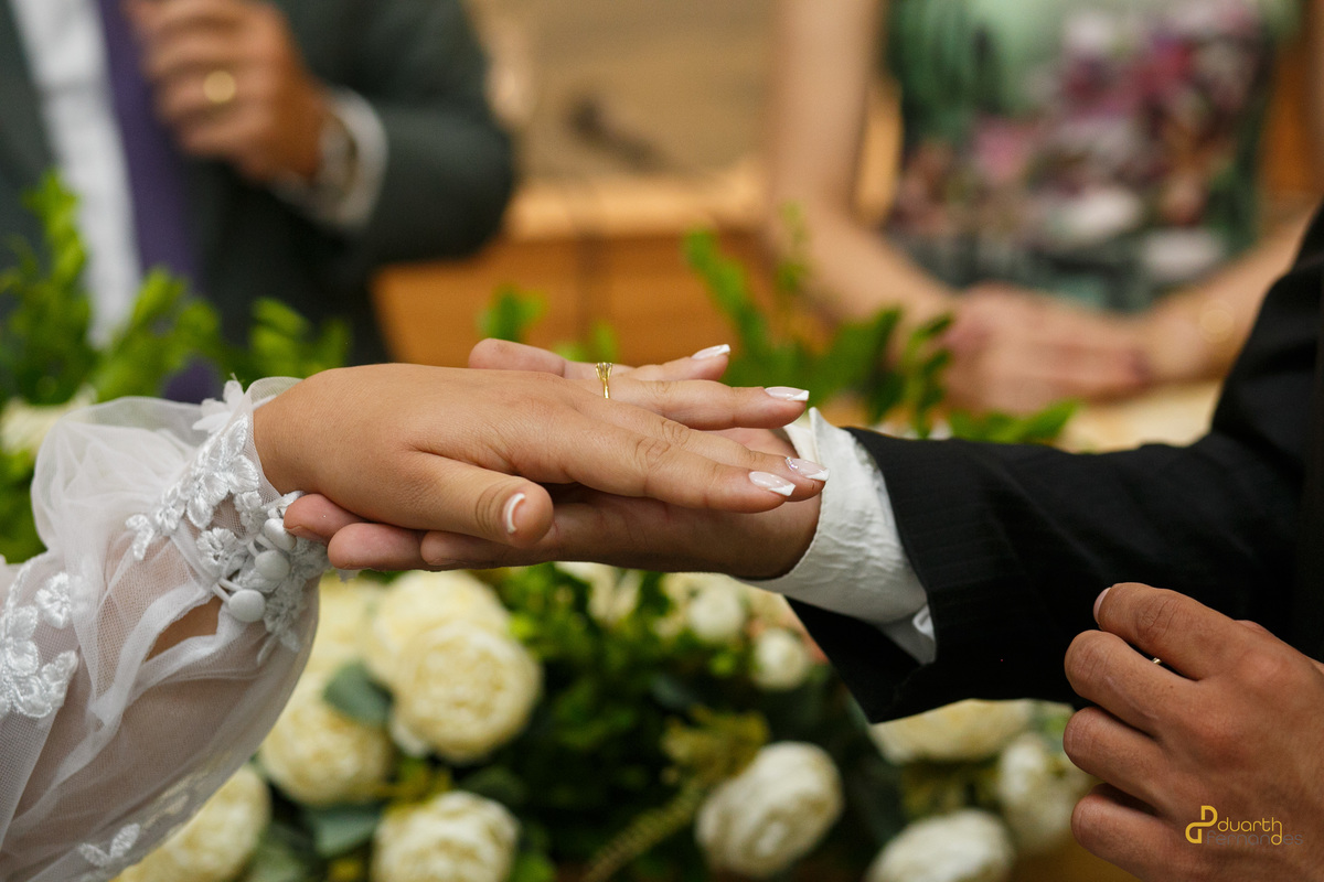 oivo Dieique beijando a mão da noiva Elen no altar durante um momento solene e emocionante. Fotografia profissional de cerimônia de casamento em Capelinha - MG.