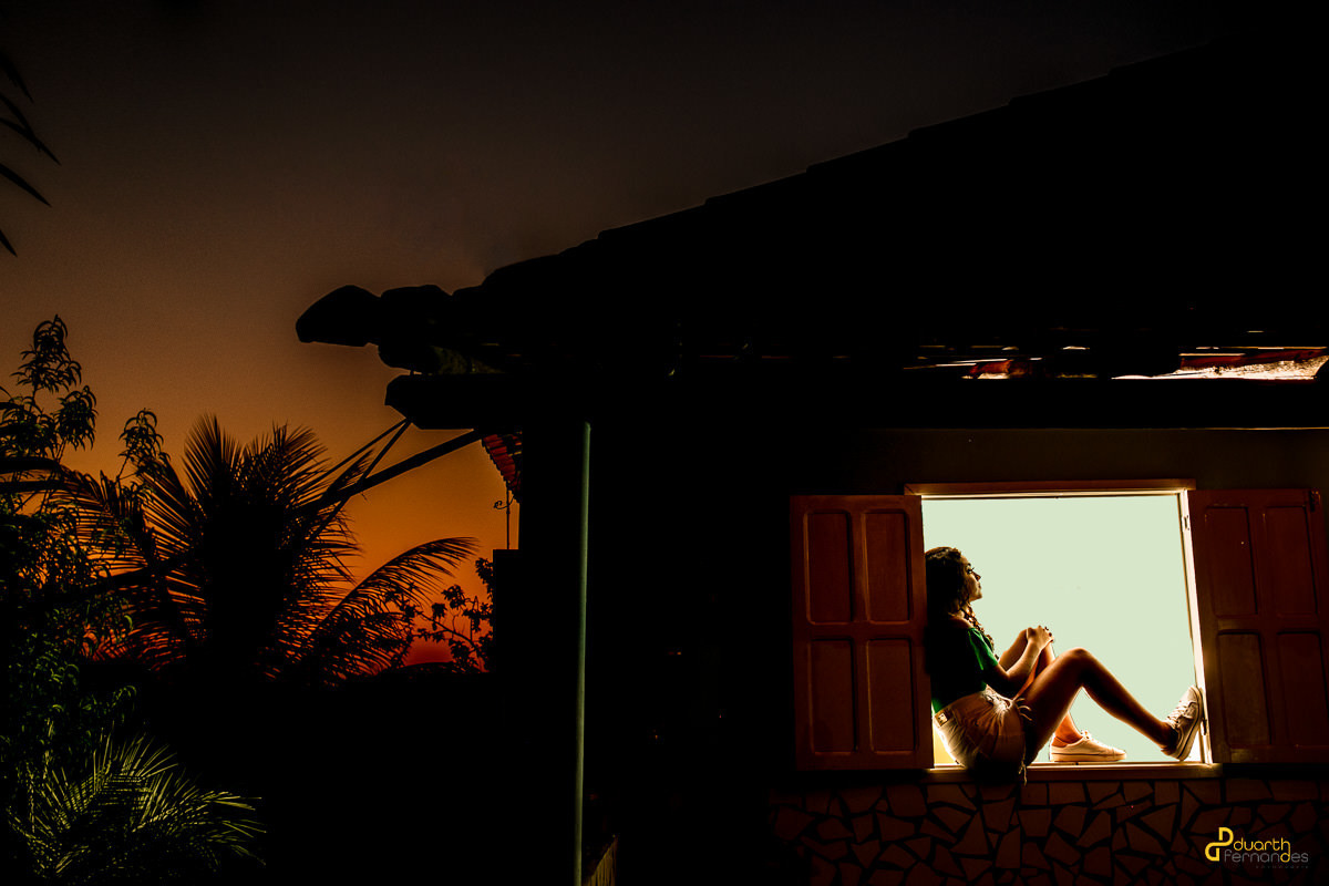 Foto de debutante no pôr do sol sentada na janela em turmalina mg