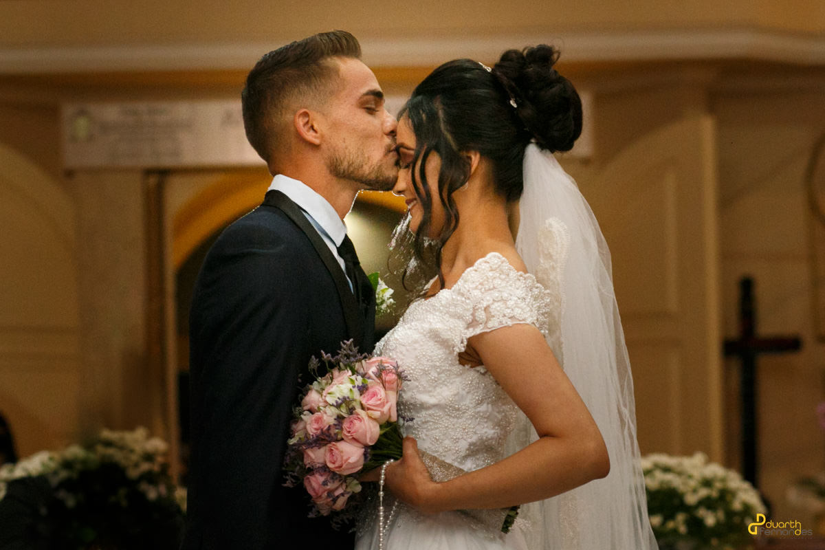 Noivo beijando a testa da noiva em igreja matriz da cidade de itamarandiba em casamento duarth fotografo