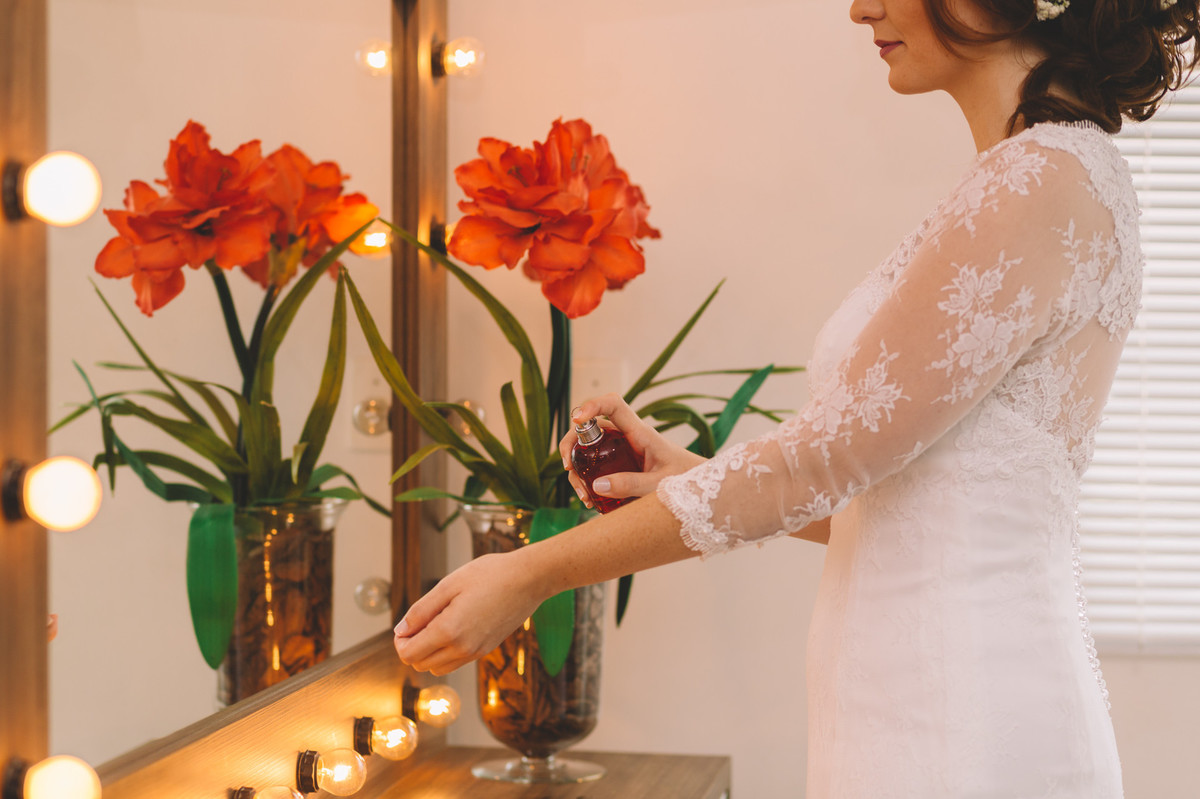 Mulher passando o perfume em frente ao espelho