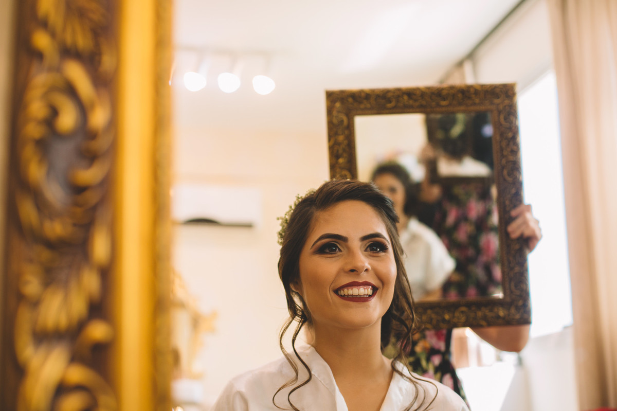 Noiva sorrindo vendo o resultado do penteado