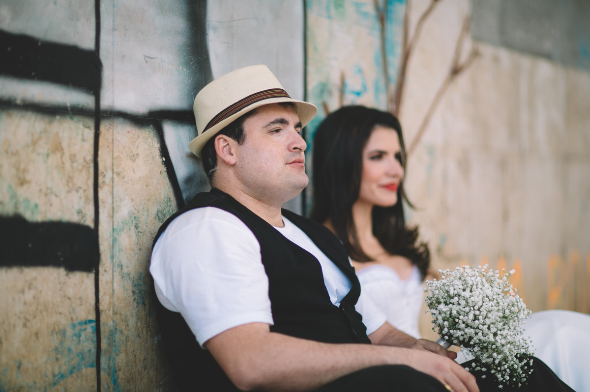 Noivos sentados na parede com grafite