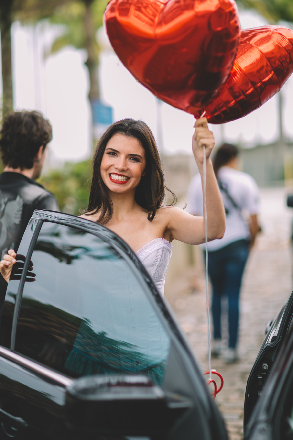 Noiva segurando dois balões de coração vermelho