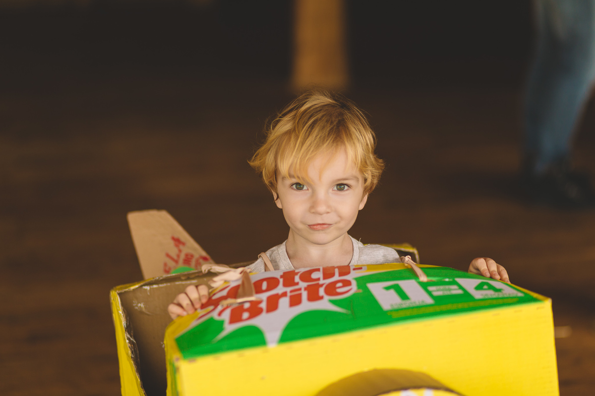 criança pequena brincando com um avião de papelão
