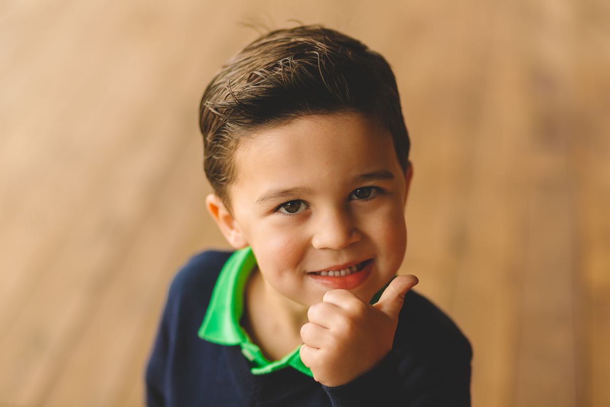 criança sorrindo e fazendo joinha com a mão