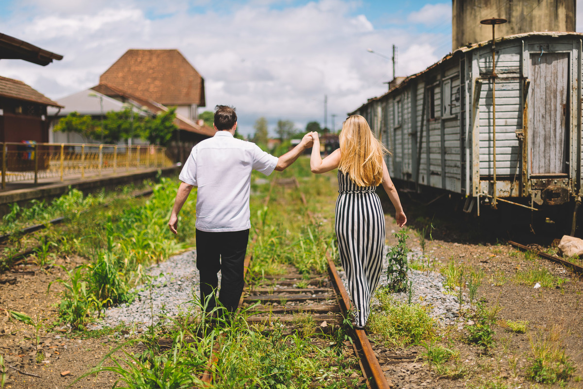 Casal andando nos trilhos do trem de mãos dadas