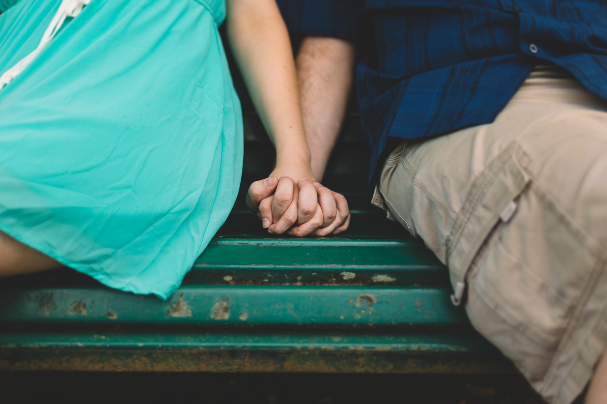 Casal de mãos dadas sentados num banco