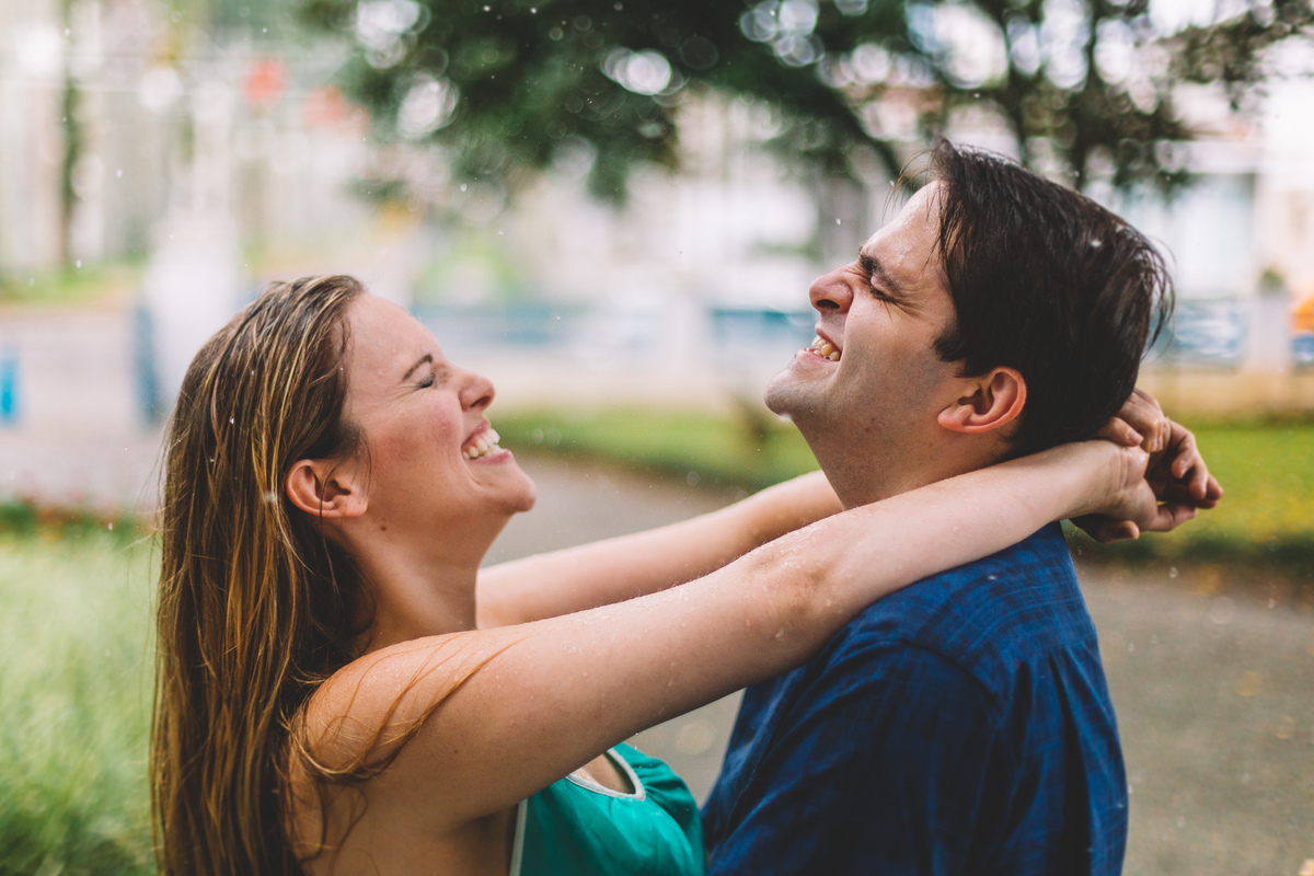 casal abraçando sorrindo na chuva 
