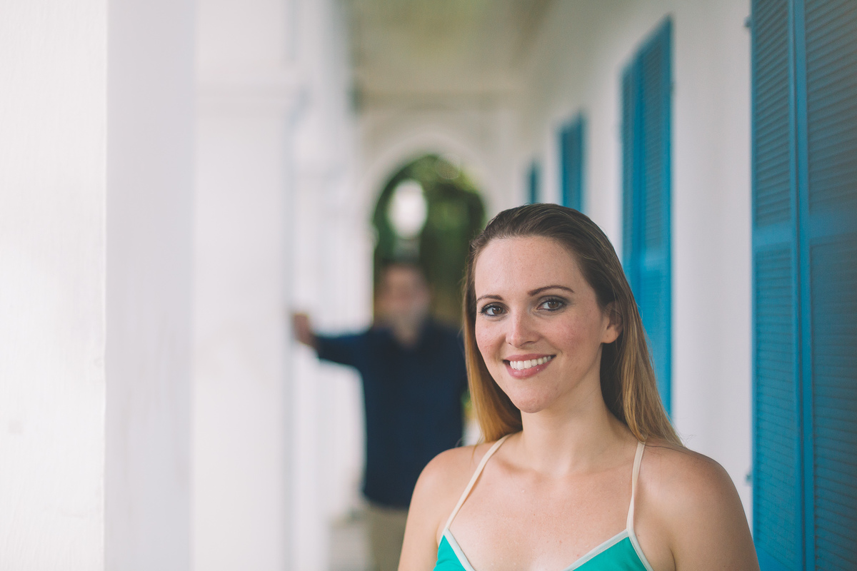 Noiva sorrindo na frente em foco e noivo atrás desfocado