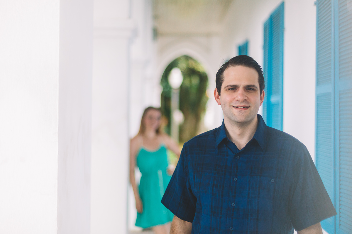 Noivo sorrindo na frente em foco e noiva atrás desfocada