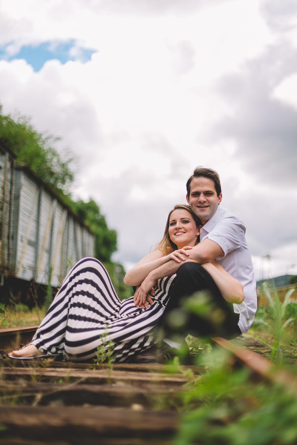 Casal abraçados sorrindo sentados no trilho 