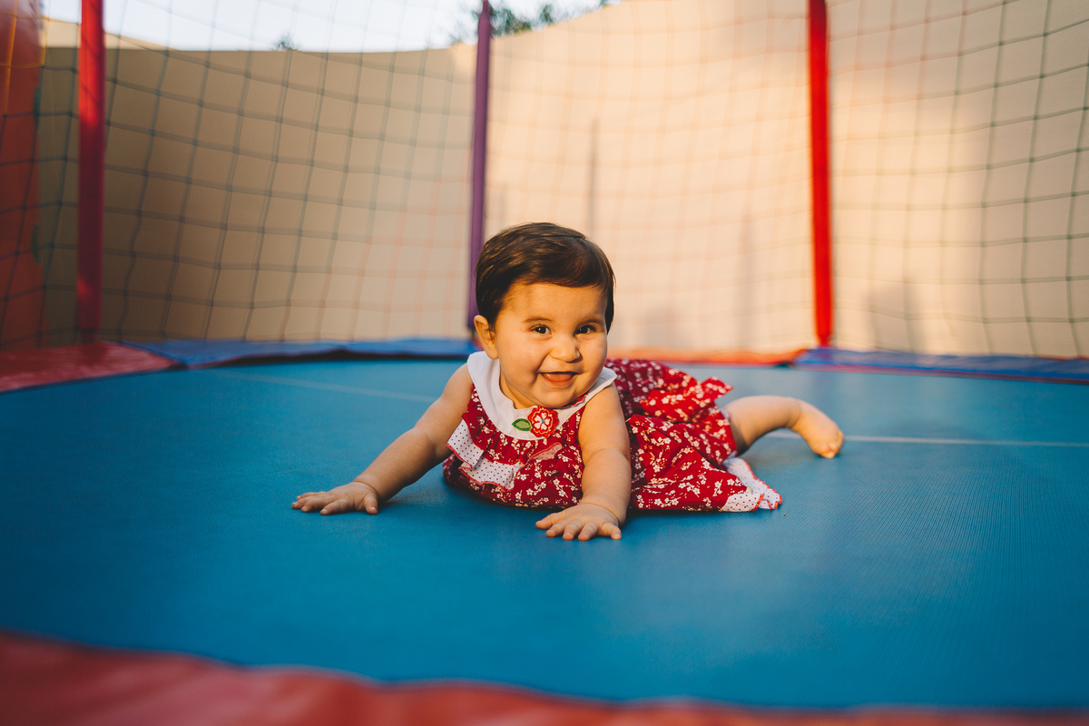 Criança rindo deitada na cama elástica