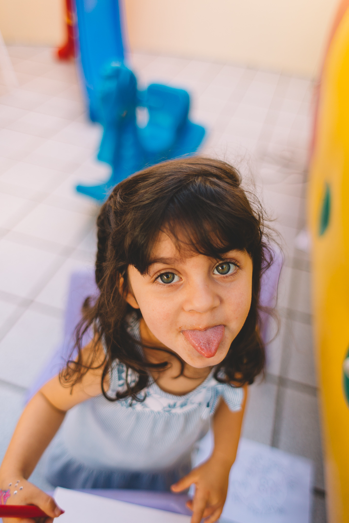 Criança de olhos verdes mostrando língua para a câmera
