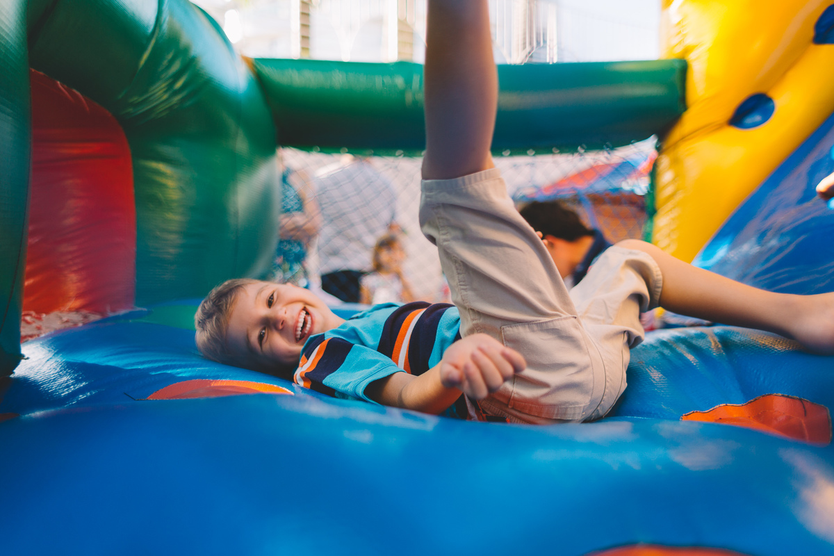 Criança se jogando e rindo no brinquedo inflável
