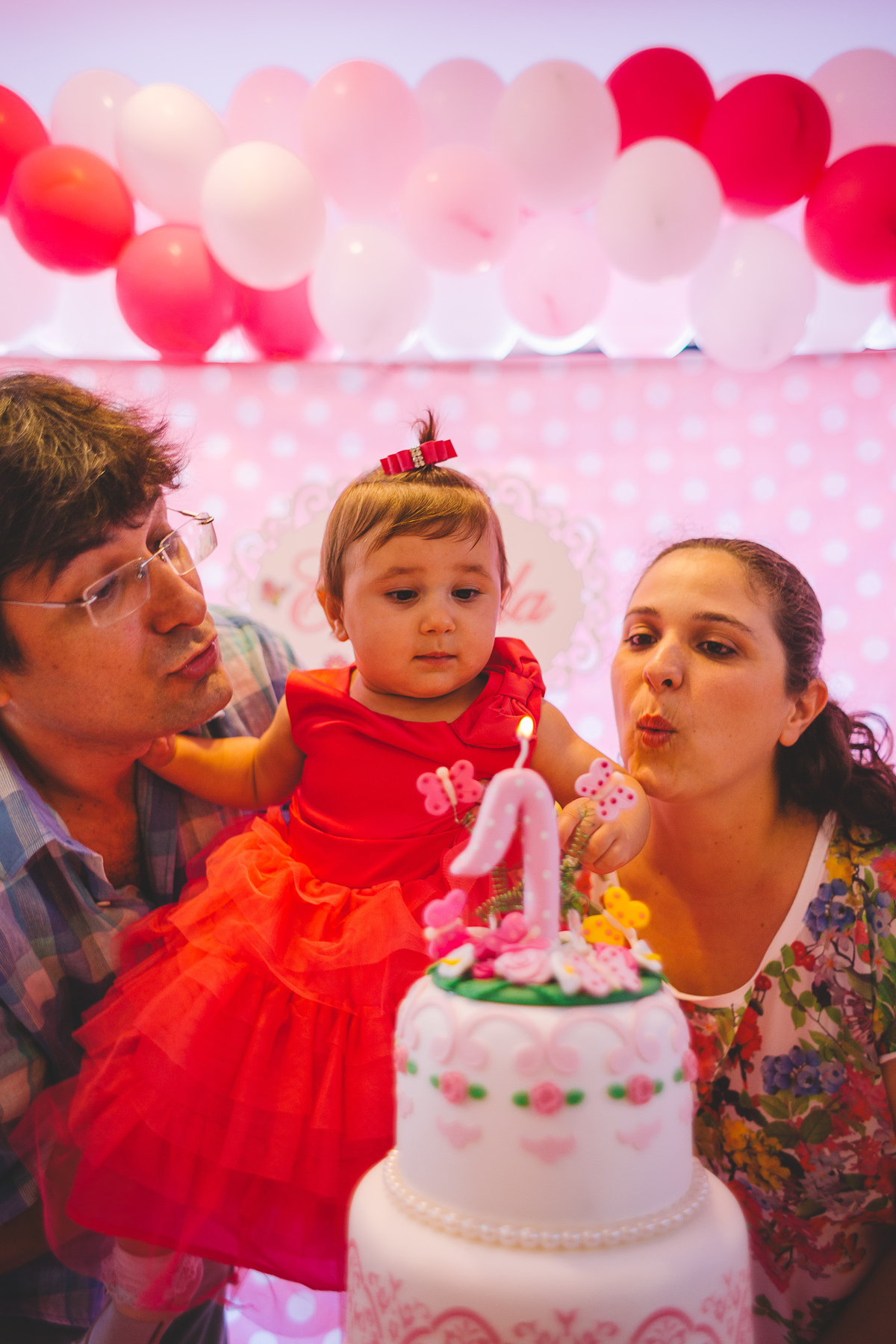 Pais e aniversariante assoprando o a vela