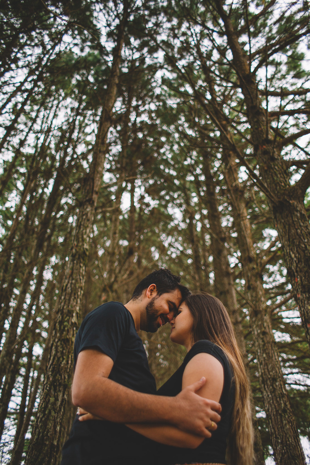 Casal de testas encostadas no meio de uma floresta