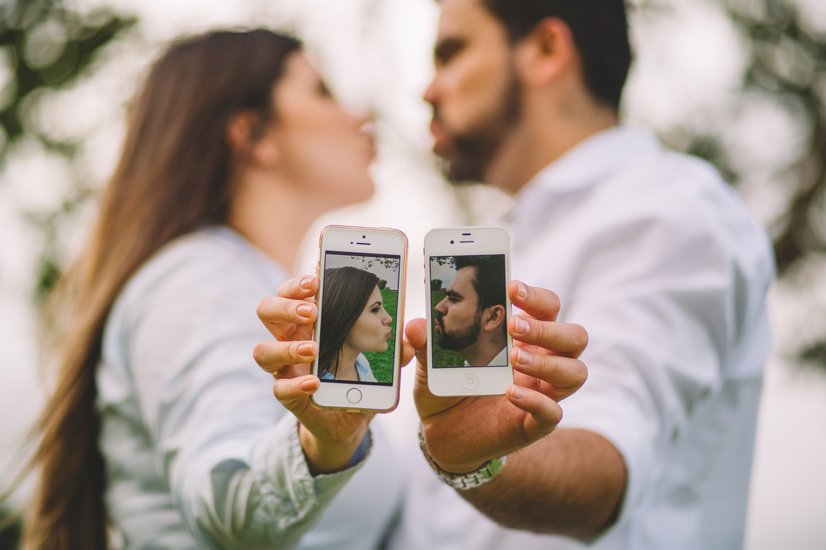 casal segurando foto e encostando os celulares para se beijarem